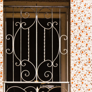 An iron screen gate to a doorway surrounded by a tile mosaic.