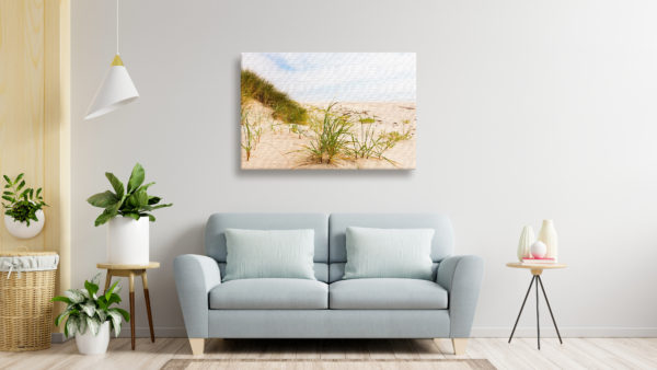 Canvas print of beach grass hung hover a couch in a living room.